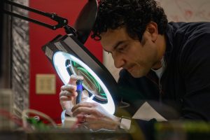 Amrou looking through a lit magnifer at a test subject