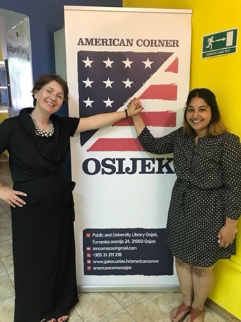 Dr. Luca Sugawara and a student standing in front of an American Corner sign